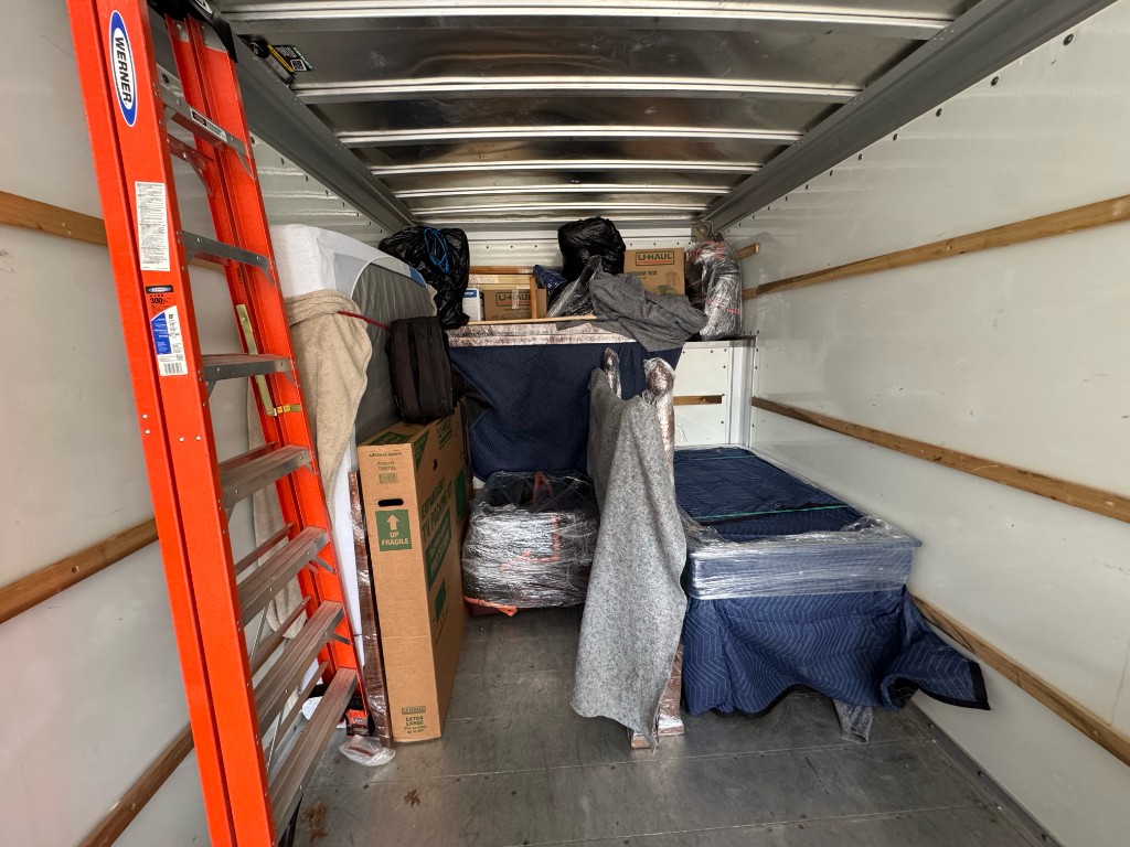 Loaded Little Fellas Moving truck with carefully wrapped furniture and moving blankets